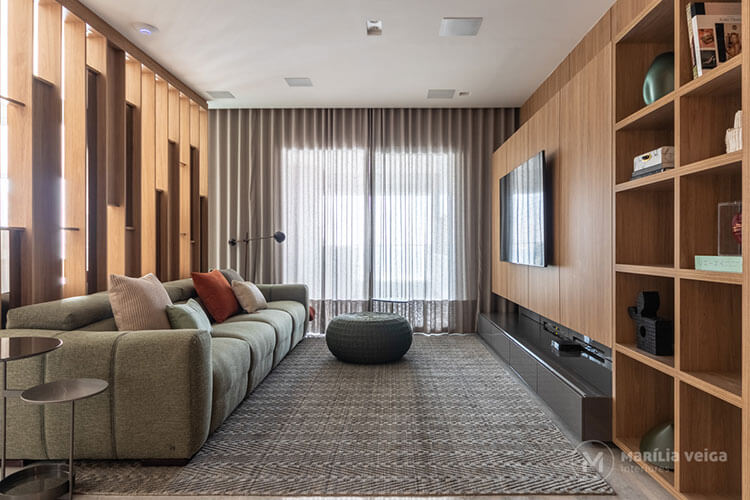 home theater integrado em ambiente com painéis de madeira e cortina