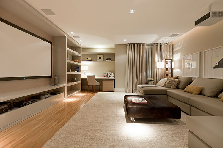 home theater integrado, móveis em tons claros, apoio de pé marrom escuro e um telão como destaque