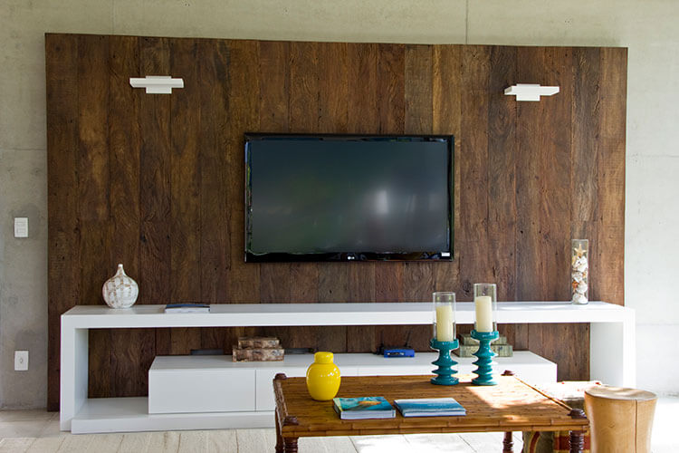 home theater integrado tv em painal de madeira escura, rack branco e mesa de centro retangular