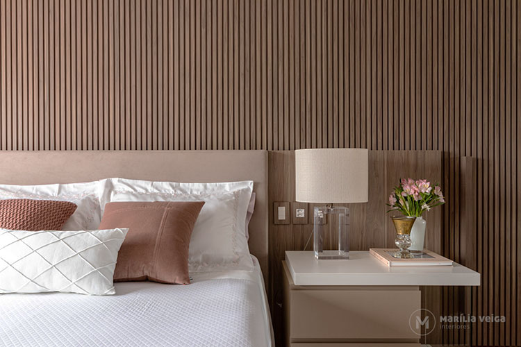 suítes de casal detalhe da cabeceira da cama com a mesa de cabeceira ao lado, decoração com painel de madeira e cores claras