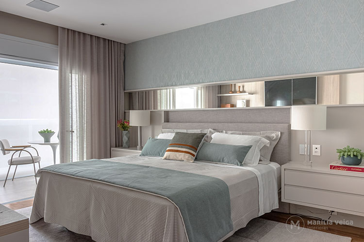 suítes de casal com decoração em tons nude e verde, com espelho acima do painel de cabeceira da cama e ampla janela que dá acesso a varanda