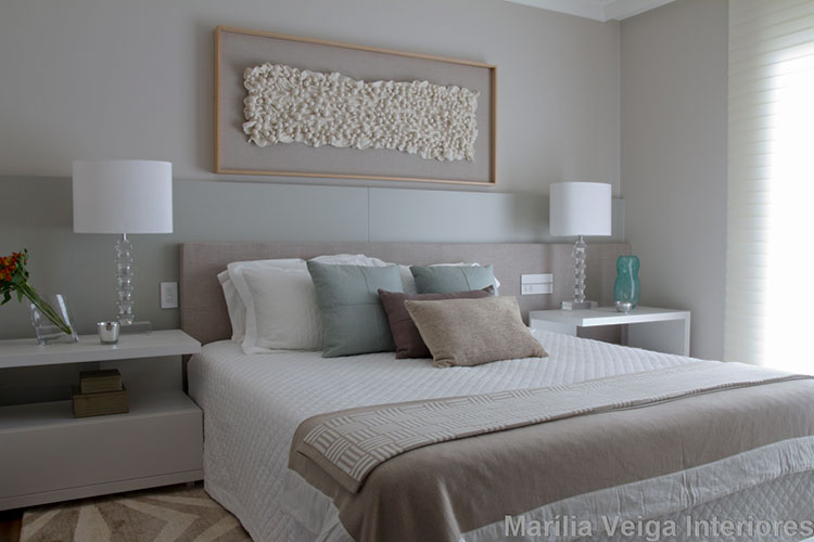suítes de casal em tons nude com painel sobreposto, quadro acima da cama e mesas de cabaceira com abajur e vaso